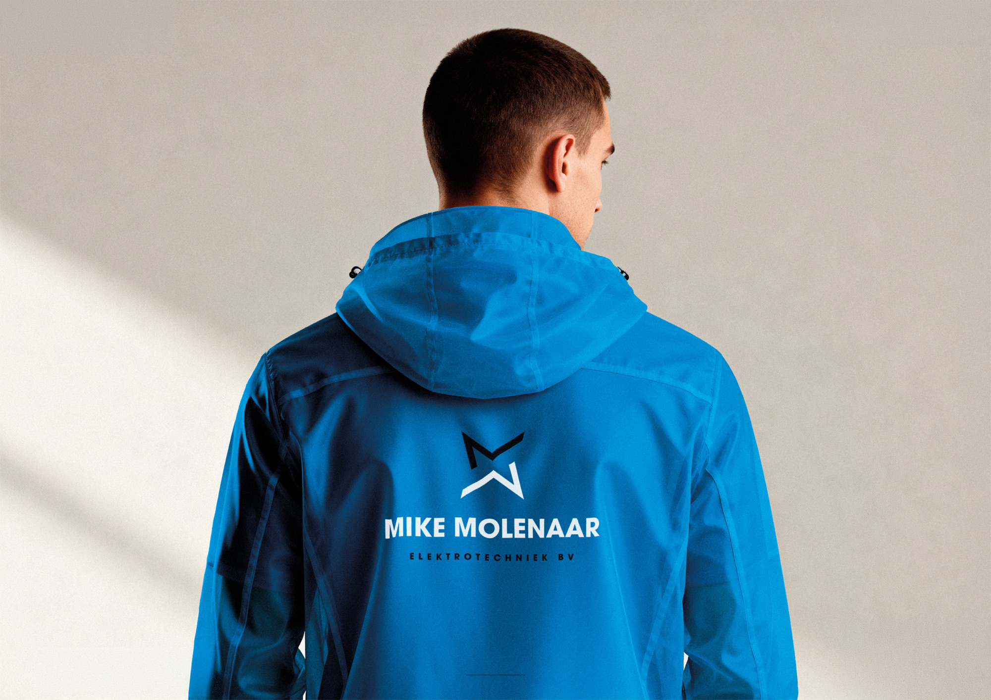 Rug van een blauwe werkjas met het logo van Mike Molenaar Elektrotechniek